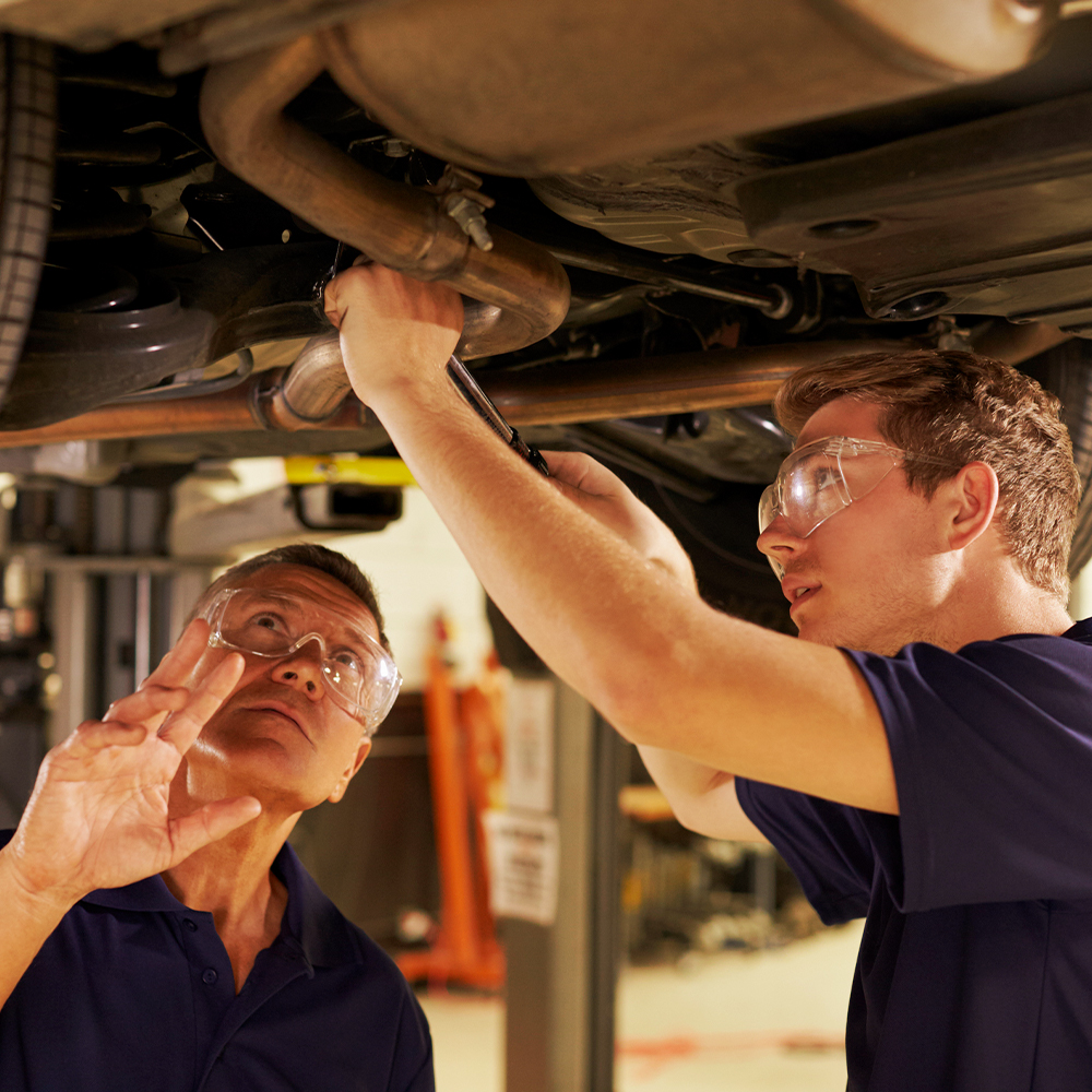 Two male mechanics inspecting the underside of a car