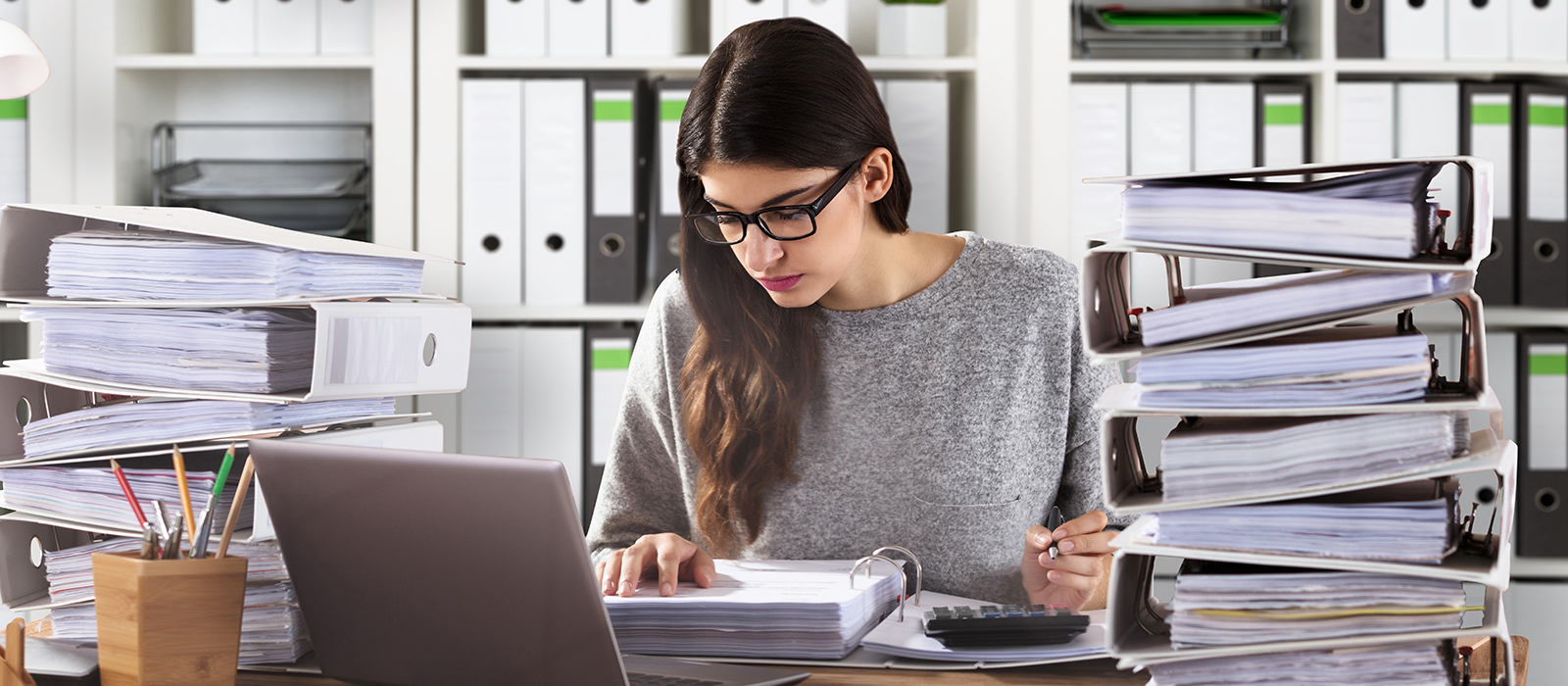 Young office worker with eyeglasses calculating papers in office