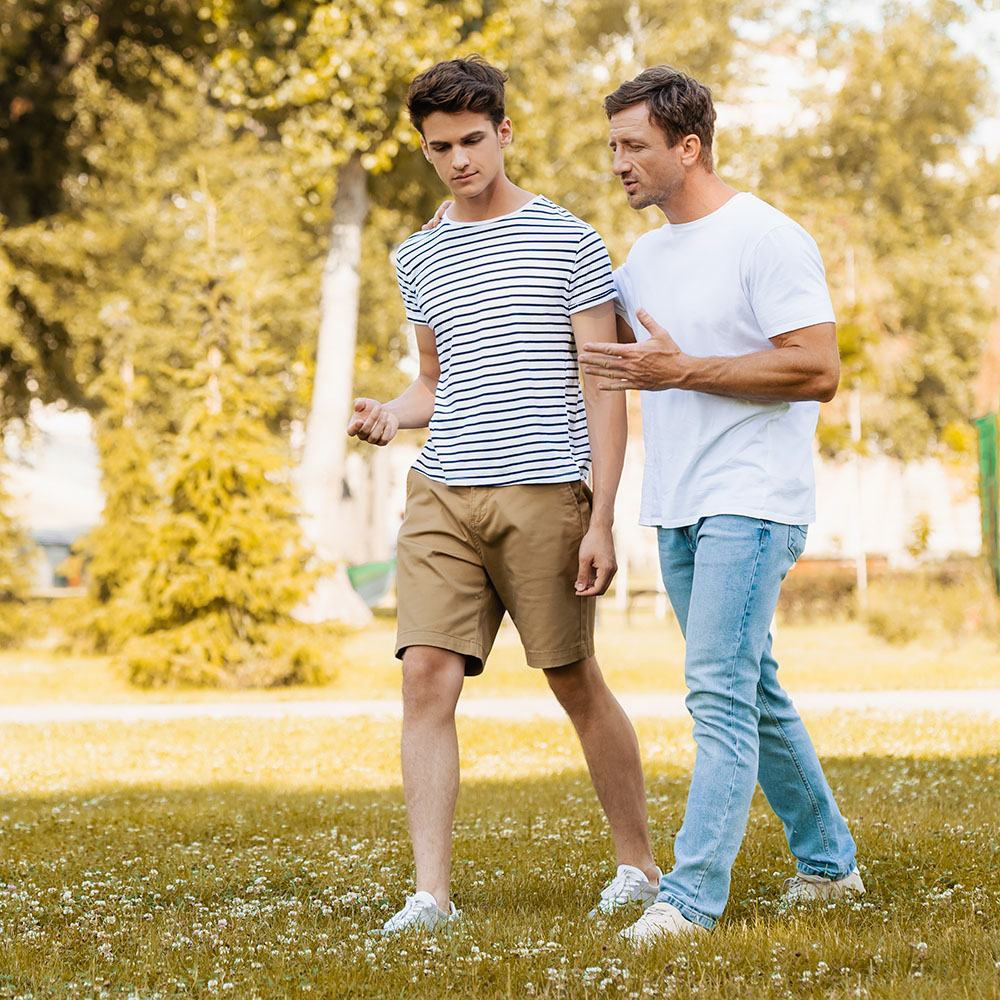 father and son walking through park talking