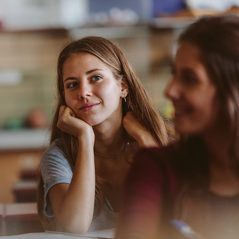 young woman sitting in classroom and looking away thinking. Female student in university classroom.