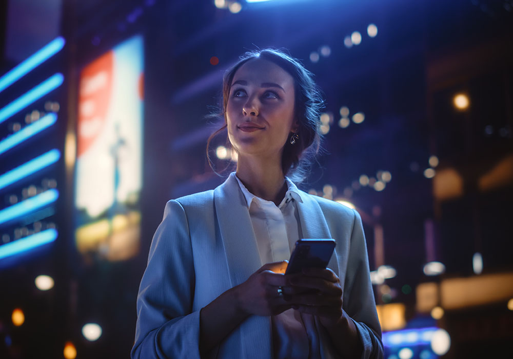 Young woman standing in city with phone