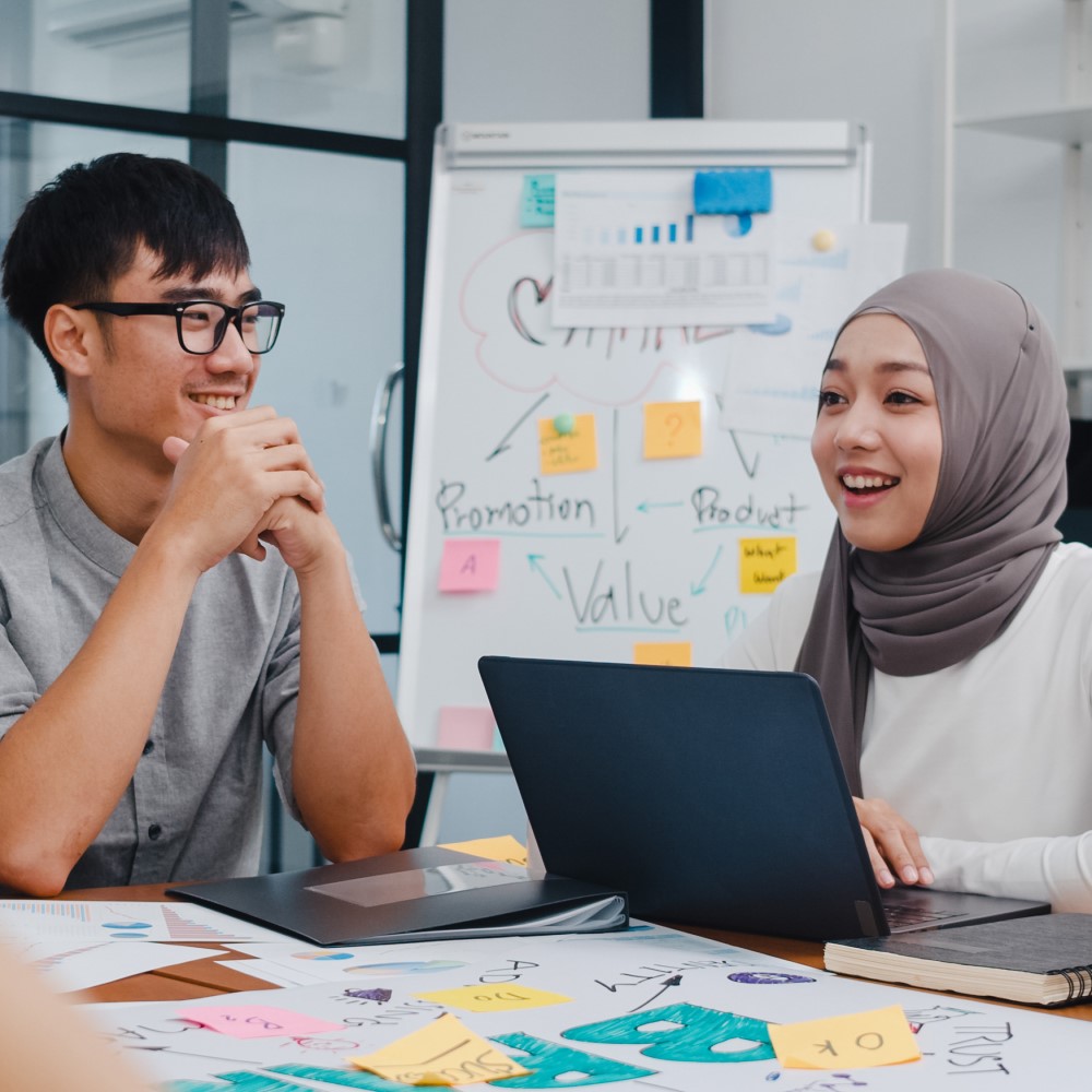 Male and female student sitting at desk smiling 