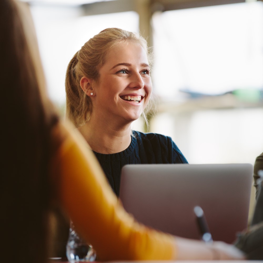 Young female student smiling in front of a computer