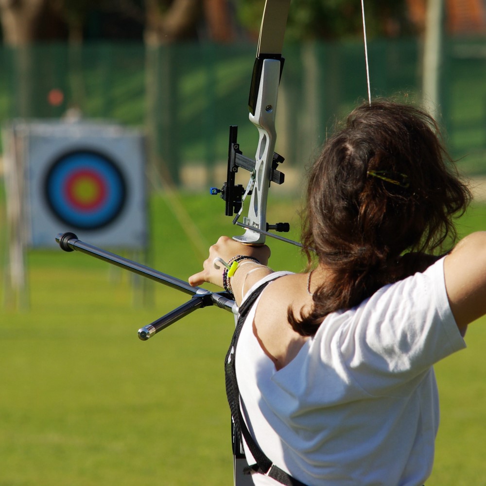Woman using archery equipment aiming at target