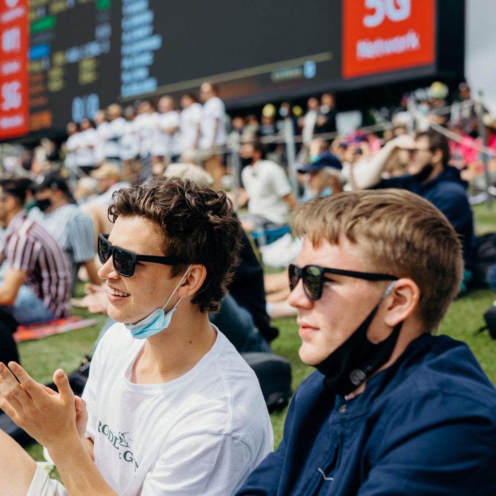 Two male teenagers at a sporting event smiling and clapping