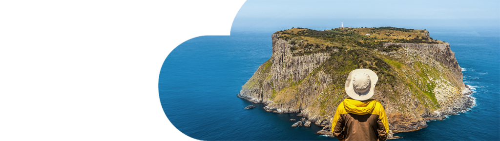 Hiker standing on cliff top overlooking island in Tasmania