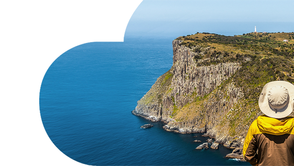 Hiker standing on cliff top overlooking island in Tasmania