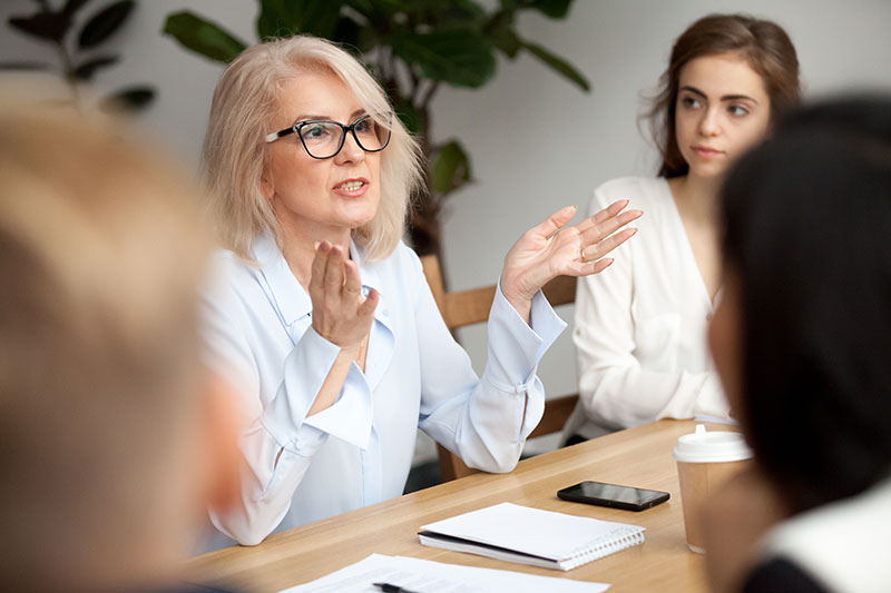 Mature woman talking with colleagues in a meeting