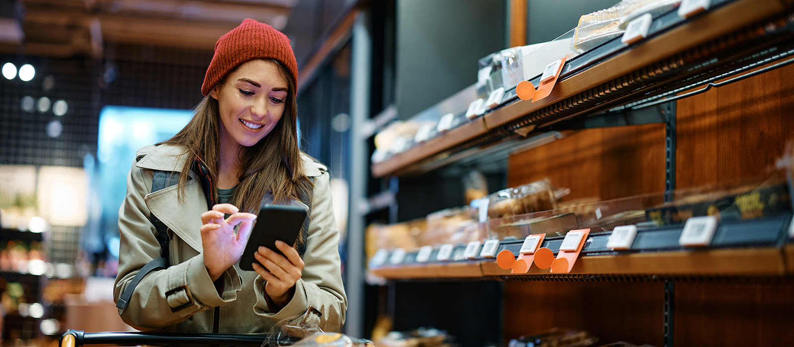 Young female at bakery checking phone budget app