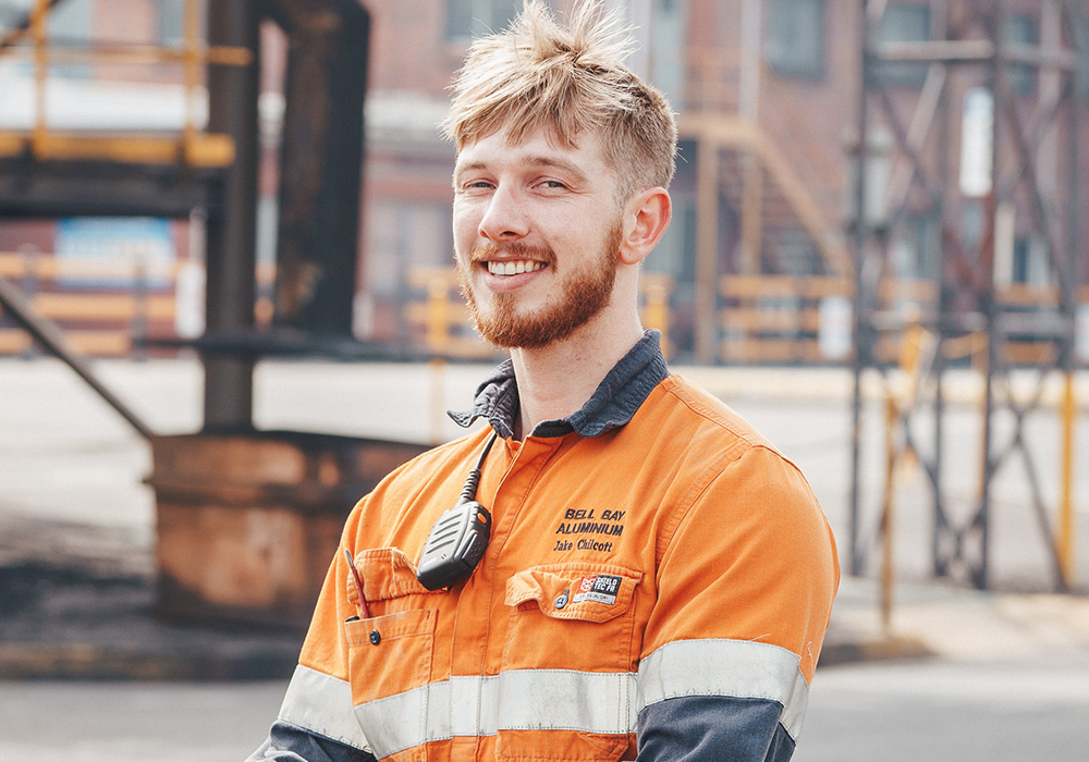 Young male worker in orange shirt smiling at the camera