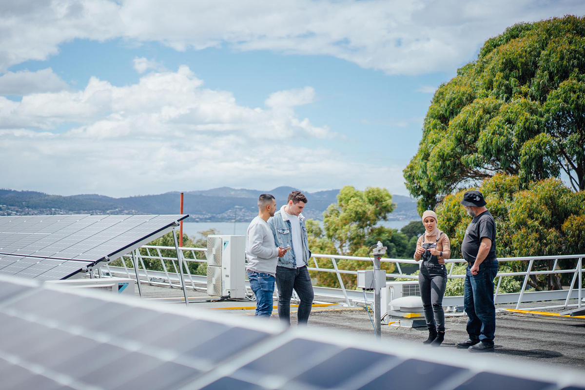 University engineering students standing on a rooftop with teacher