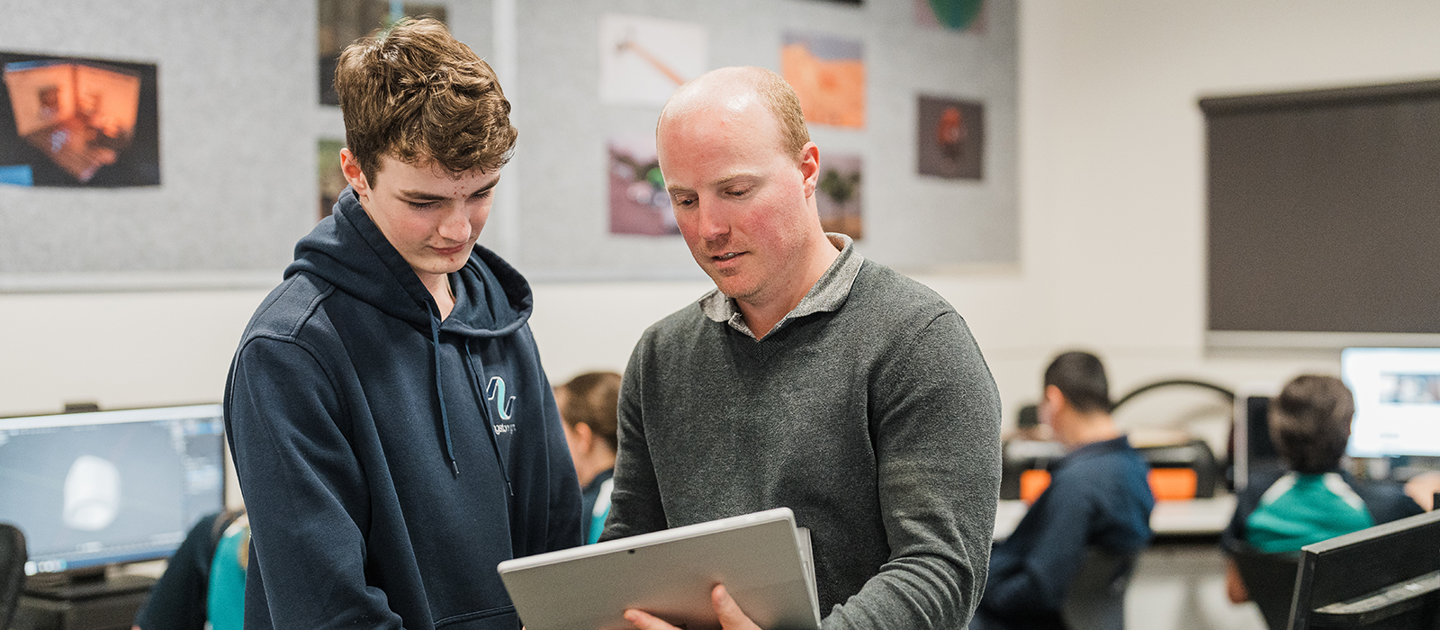 Male teacher and student holding a computer