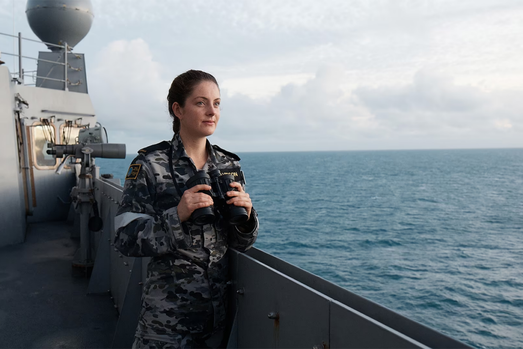 Female navy personnel on a ship using binoculars