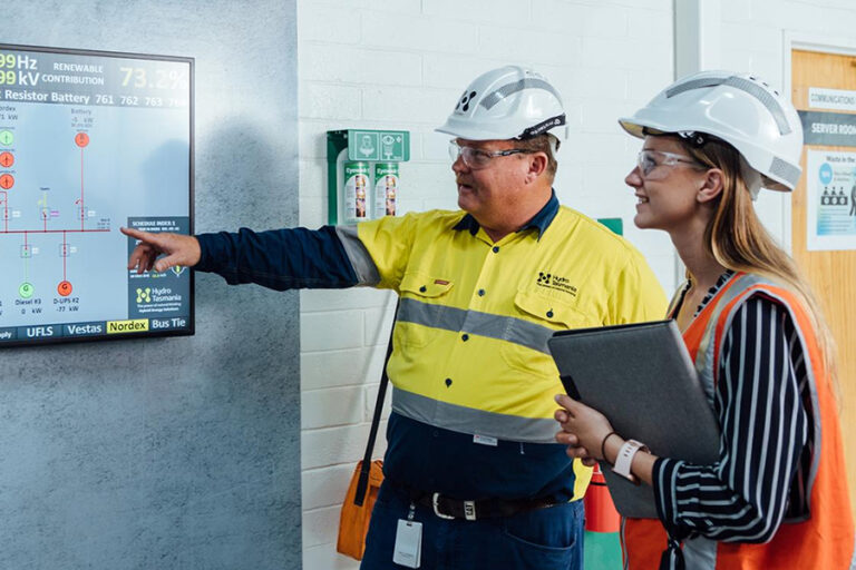 Two energy workers inspecting system management diaplay