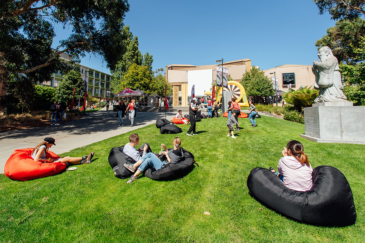 Students sitting on a green lawn at a university campus