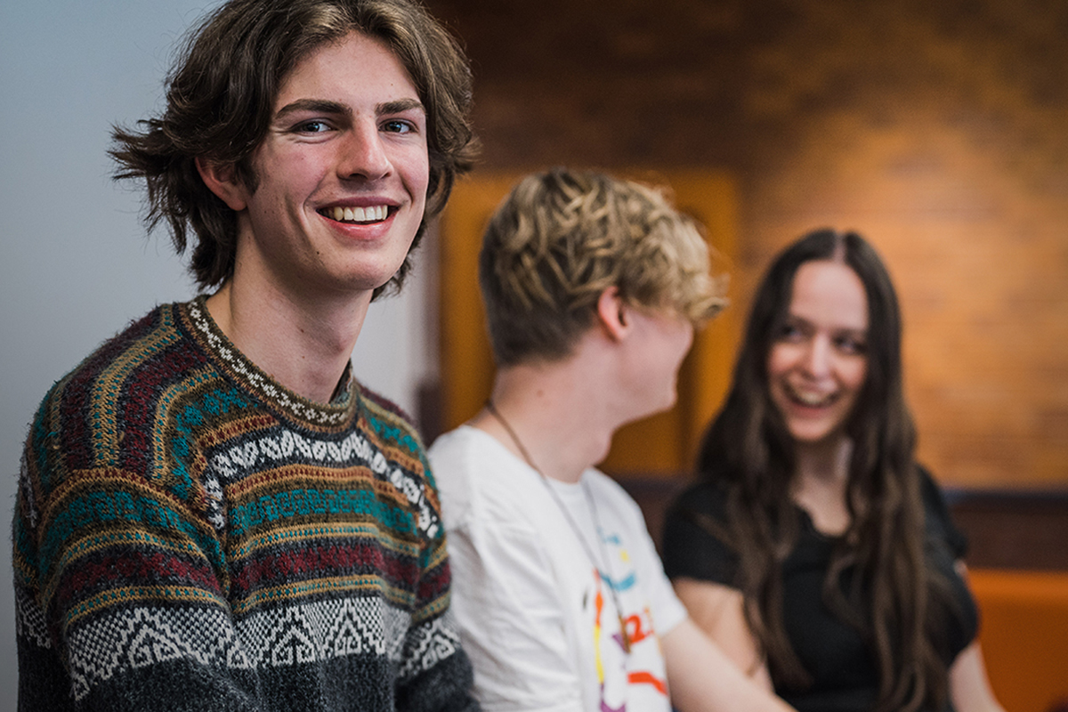 College students sitting at a desk talkking. Mature male student smiling at the camera