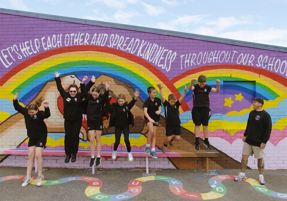Happy primary school students jumping off a bench