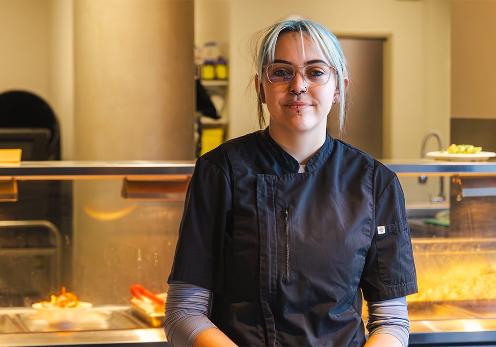 Young female chef wearing glasses sitting and smiling at the camera