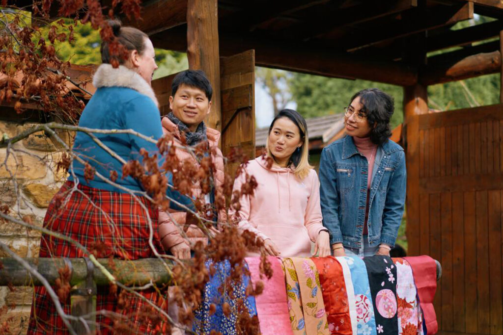 Group of cultirallly diverse people standing in a Japanese garden talking and smiling