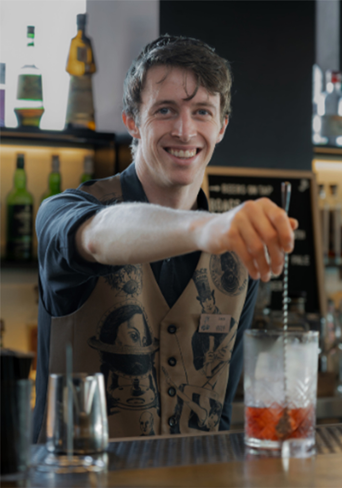 Young male hospitality worker mixing a cocktail drink