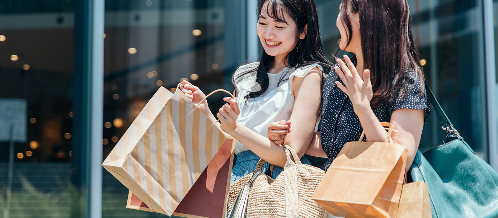 Two young asian women smiling and holding shopping bags