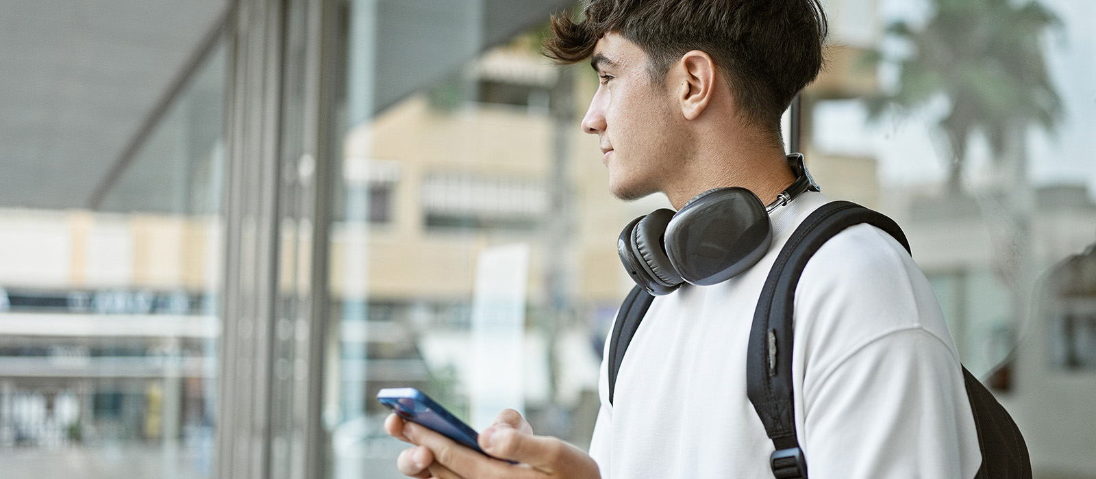 Young male holding mobile phone and wearing headphones