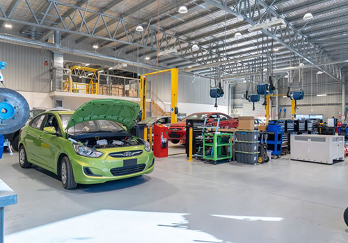 Inside of an automotive training facility building showing repair equipment and vehicles